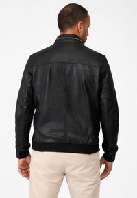 Black leather jacket with a smooth texture, ribbed knit trim at the cuffs and hem, and a classic collar. Visible stitching details.
