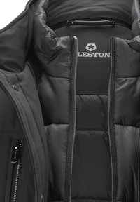 Schwarze Pufferjacke mit glatter Oberfläche, gesteppter Textur und auffälligen Reißverschlüssen. Das Innenfutter verfügt über ein Logo und ein gepolstertes Design zur Isolierung.