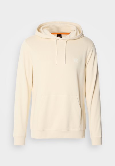 Sweatshirt à capuche couleur crème en tissu doux, avec une poche frontale, des cordons de serrage et un petit logo sur la poitrine.