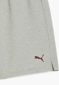 Puma Sportshorts aus hellgrauem Stoff, mit einem burgunderfarbenen Logo, einem flachen Bund und seitlichen Schlitzen für zusätzliche Bewegungsfreiheit.