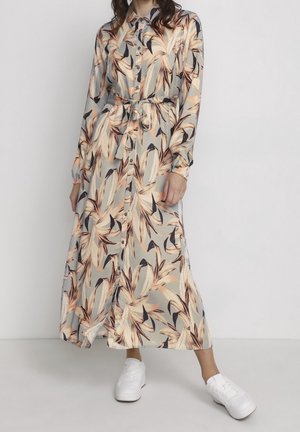 Langes Hemdblusenkleid aus hellgrauem Stoff mit einem blattartigen Blumenmuster in Orange und Braun. Mit langen Ärmeln und einem gebundenen Taillenbereich.