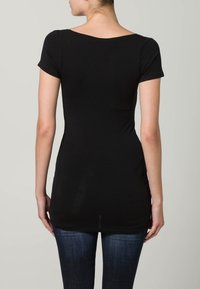 Fekete, testhez simuló póló rövid ujjakkal, kerek nyakkal és varrat nélküli hátrésszel. Puha, rugalmas anyagból készült; az alja kissé a csípő alatt végződik.