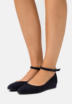 Ballerine in suede blu navy con punta rotonda, cinturino alla caviglia e tacco basso a cuneo. Texture liscia, design minimalista e stile slip-on.