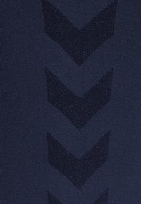 Marinblå sporttyg med en texturerad chevronmönster. Slät yta med kontrasterande mörkare chevrons genom hela materialet.