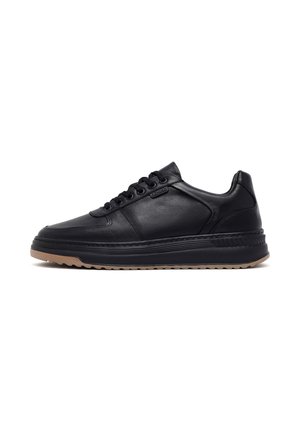 Black leather sneaker with round toe, lace-up design, and textured accents. Features a rubber sole with a contrasting tan base.