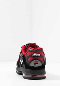 Baskets noires et rouges avec des matériaux doux, un design en spirale, des accents en maille et un coussin d'air transparent dans la semelle. Présente un logo sur le talon.