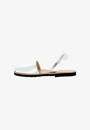 Witte leren platte sandaal met gesloten teen, open achterkant en enkele band rond de hiel, zwarte zool en beige binnenzool.