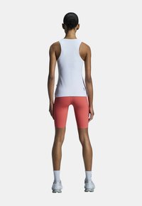 Strakke witte tanktop met smalle bandjes, gecombineerd met koraalkleurige shorts. Ontworpen met gladde stof en minimalistische merkdetails.