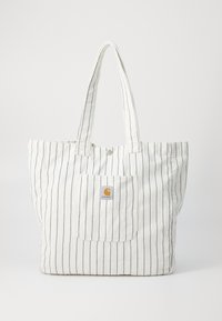 Bolsa de lona blanca con rayas verticales en azul marino, dos asas largas y un bolsillo frontal que presenta un pequeño parche del logo.