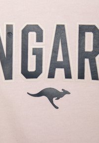 Hellrosa Stoff mit kräftigen, dunkelgrauen Buchstaben, die "KANGAROO" lesen, mit strukturierter Oberfläche und einer kleinen Känguru-Silhouette unter dem Text.
