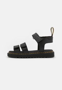 Black leather sandals featuring three adjustable straps, a textured sole, and yellow stitching along the edge. Back pull tab for easy wear.
