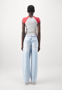 Grå och röd kortärmad topp som är ihop med lösa, ljusblå, slitna denimjeans med bakfickor och en urblekt finish.