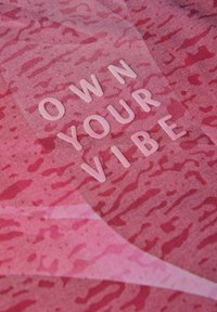Textil en diferentes tonalidades de rosa con un patrón abstracto texturizado. La frase "POSEE TU VIBRA" está moldeada en letras blancas brillantes.
