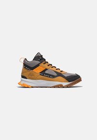 Chaussure de randonnée mi-haute en gris, noir et orange avec tissu Gore-Tex, semelle en caoutchouc texturée et logo Timberland sur le côté.