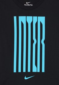 T-shirt noir avec de larges rayures verticales bleues et le mot "INTER" dans une police stylisée. Logo Nike en bleu en bas.
