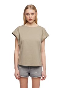 Top beige a maniche corte con scollo rotondo e dettagli metallici decorativi sui polsini arrotolati. Abbinato a shorts in denim grigi.