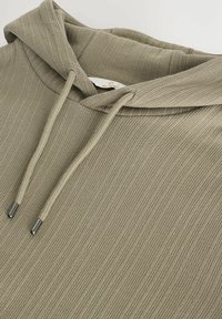 Sudadera de color caqui con costillas y capucha ajustable con cordones, que presenta puntas metálicas en los cordones y una tela texturizada.