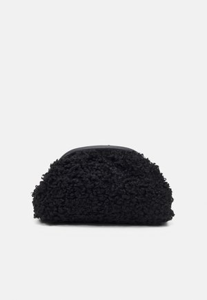 Mała czarna sakiewka z teksturowaną, kręconą tkaniną i gładką górną krawędzią, na jasnym, jednolitym tle.