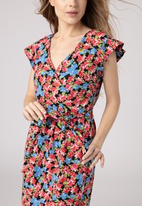 Robe portefeuille florale avec un fond noir et des fleurs rouges, bleues et vertes, manches courtes à volants et détail de taille nouée.