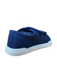 Zapatilla de lona azul con suela de goma blanca y agarre texturizado. Cuenta con una correa de velcro, forma redondeada y acentos cosidos.