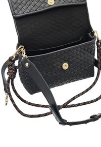 Sac bandoulière en cuir tressé noir avec ferrures dorées, sangle réglable à motif et fermeture à bouton. L'intérieur comprend un compartiment principal.