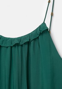 Camisole teal cu un decolteu cu volane, bretele subțiri ajustabile cu accente aurii și o textură de țesătură moale și fluidă.