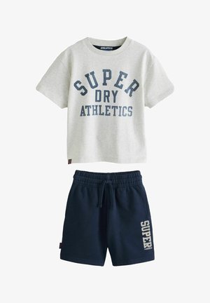 Lysegrå T-shirt med korte ærmer med teksten "SUPER DRY ATHLETICS" og marineblå shorts med elastisk talje og teksten "SUPER DRY" på venstre ben.
