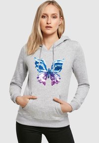 Felpa grigia con cappuccio caratterizzata da una grafica colorata di una farfalla nelle tonalità blu e viola, dotata di tasca frontale e cappuccio regolabile con cordino.