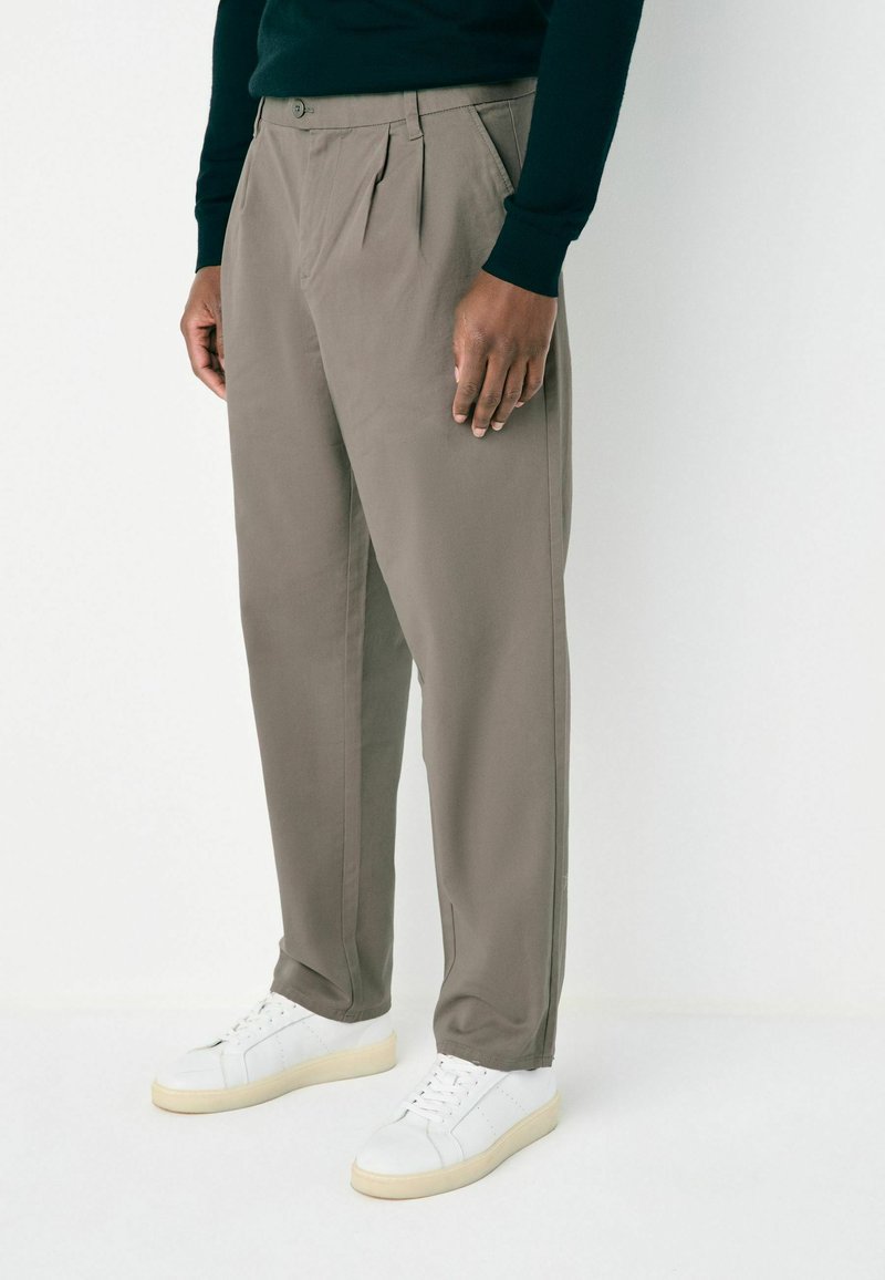 Gray pleated trousers made of lightweight fabric, featuring a tailored fit and side pockets, paired with white sneakers.