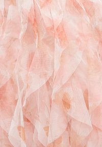 Απαλό ροζ διαφανές ύφασμα με στρωμένες βολάν και λεπτά ροδακινί λουλουδάτα σχέδια που δημιουργούν μια λεπτεπίλεπτη υφή.