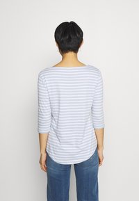 Ljusblå och vit randig långärmad topp med en rundad nederkant. Mjuk tyg, lös passform och trekvartslånga ärmar. Bärs med blå jeans.