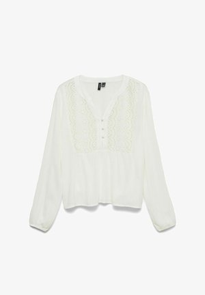 Hvit bluse med lange ermer, med bølget blondesøm på brystet, tre stoffkledde knapper, rund halslinning og elastiske mansjetter.