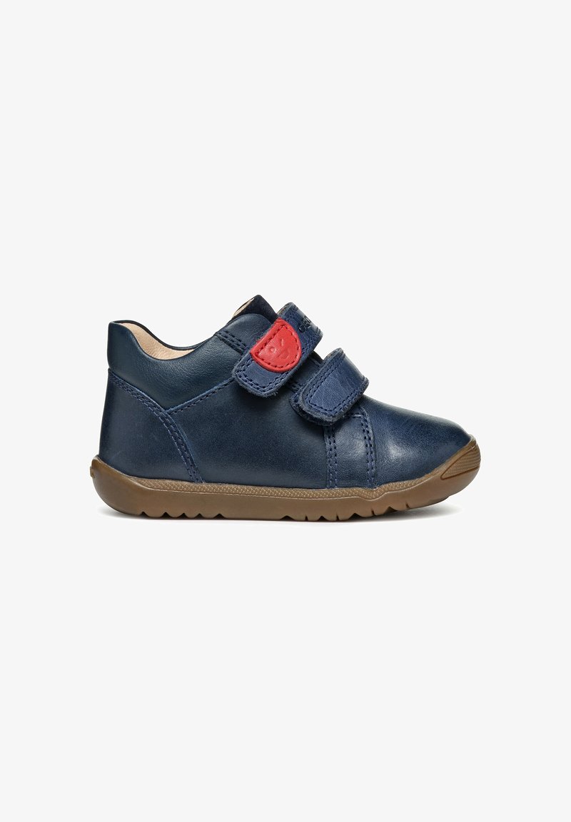 Marineblaue Kleinkinderschuhe mit brauner Sohle, zwei verstellbaren Riemen, von denen einer ein rotes Patch mit einem lächelnden Gesicht zeigt.
