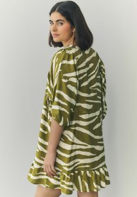 Grünes und weißes Tiermotivkleid mit kurzen Ärmeln, gerafftem Saum und lockerer Passform, aus einem weichen, strukturierten Stoff.