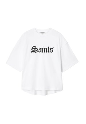 Hvid oversized T-shirt med korte ærmer og sort tekst i gammelengelsk skrifttype "Saints" centreret på forsiden.