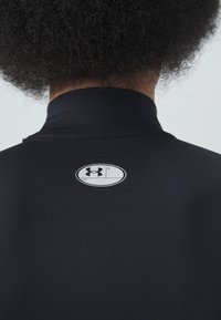 Black athletic shirt featuring a high collar, smooth texture, and a prominent oval logo on the back with a blank name tag area.