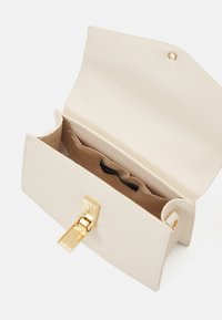 Beige leren clutch met een gestructureerde vorm, voorzien van een sluiting in goudkleur en een zachte binnenkant, inclusief een label en kaarthouders.
