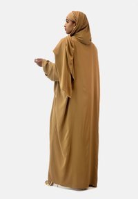 Brun, flödande abaya gjord av mjukt, lätt material. Har långa ärmar och en matchande hijab. Enkel design utan mönster eller accenter.
