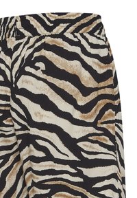 Gros plan sur un tissu à rayures zébrées noir, blanc et marron avec une ceinture froncée, montrant un matériau texturé et légèrement froissé.