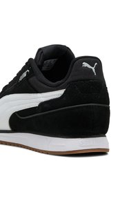 Zapatilla deportiva en blanco y negro que presenta materiales de ante y tela, con una suela de goma y un distintivo logo de Puma en el talón.