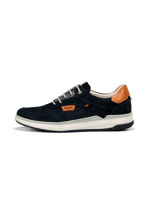 Zapatilla baja negra y marrón con suela blanca, cordones grises y parche con el logo naranja de Fluchos en el lateral.