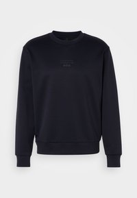 Sweat-shirt noir à manches longues et col rond avec un logo discret "Porsche BOSS" sur la poitrine, poignets et ourlet côtelés.