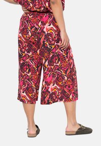 Kleurige culottebroeken met een draaiend bloemenpatroon in roze, rood en zwart. De stof lijkt lichtgewicht met een elastische tailleband.