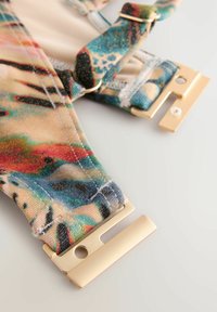 Cinghie in tessuto colorato con un motivo astratto, dotate di accessori metallici dorati per le regolazioni. Texture liscia e design multicolore.
