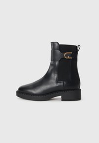 Bottine en cuir noir avec panneaux élastiques sur les côtés, talon carré et accent en métal doré. Texture lisse et design à bout arrondi.