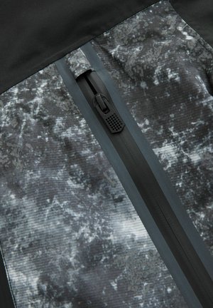 Czarny i szary materiał tekstylny z textured, abstrakcyjnym wzorem. Posiada zamek błyskawiczny z przodu z czarnym uchwytem oraz kontrastowym szarym wykończeniem.