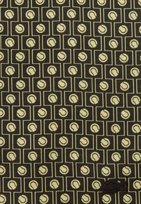 Must kangas, millel korduvad kollased tennisepalli motiivid ruudukujulistes raamides ja väike tikitud krokodillilogoga alumises paremas nurgas.