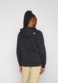 Black hoodie with a spacious hood, ribbed cuffs, and hem. Features a small white logo on the upper back. Smooth, comfortable fabric.