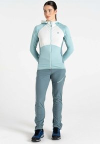 Leichte, zweifarbige Sportjacke in Blau und Weiß, mit durchgehendem Reißverschluss und Kapuze; kombiniert mit grauen Hosen und blauen Schuhen.