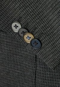 Grau strukturiertes Gewebe mit einem Blazer-Revers und vier Knöpfen in Hellgrau, Dunkelgrau, Beige und Schwarz, jeweils mit einem Vierlochdesign.